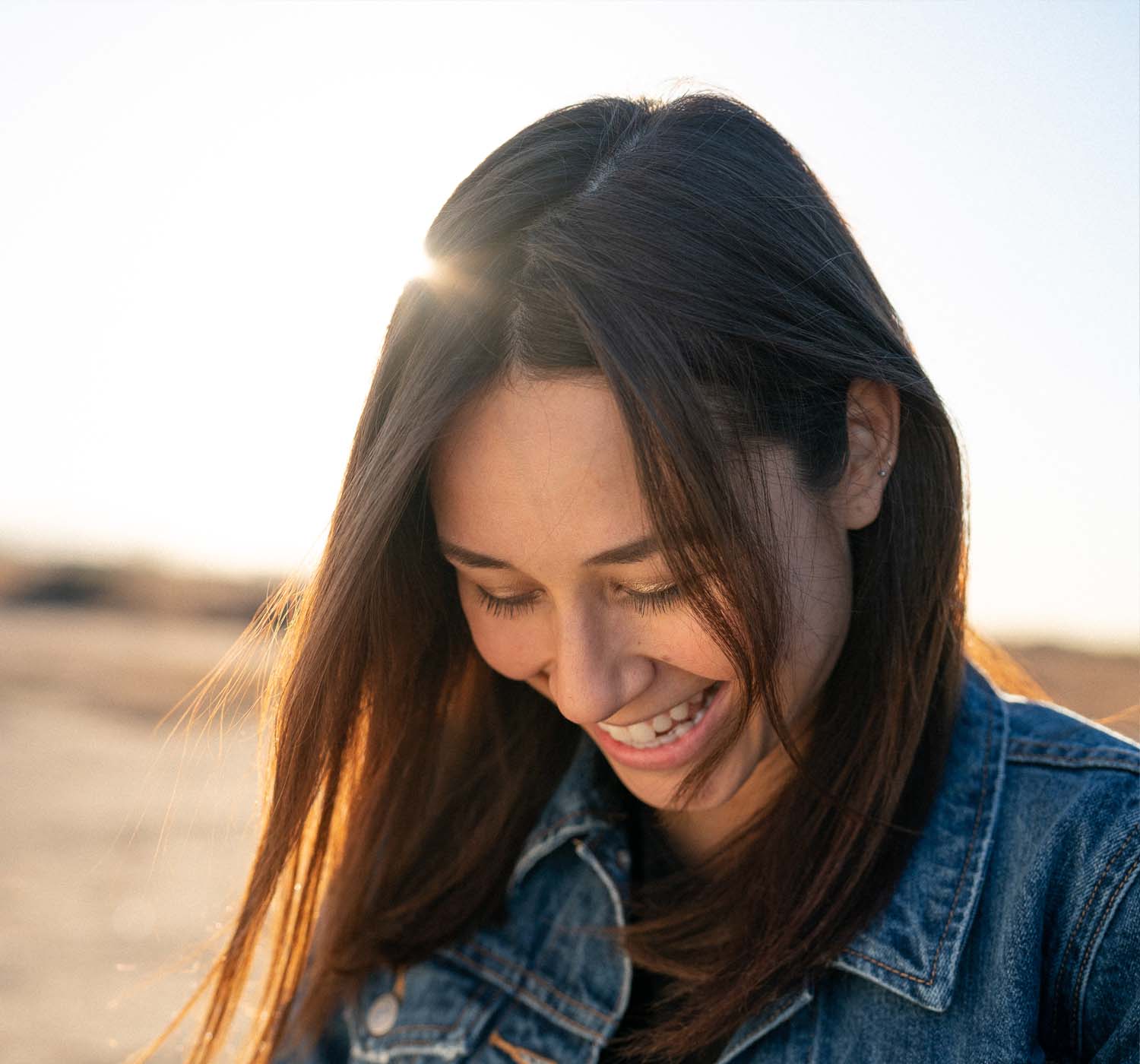 woman smiling with sun in background woman smiling with sun in background